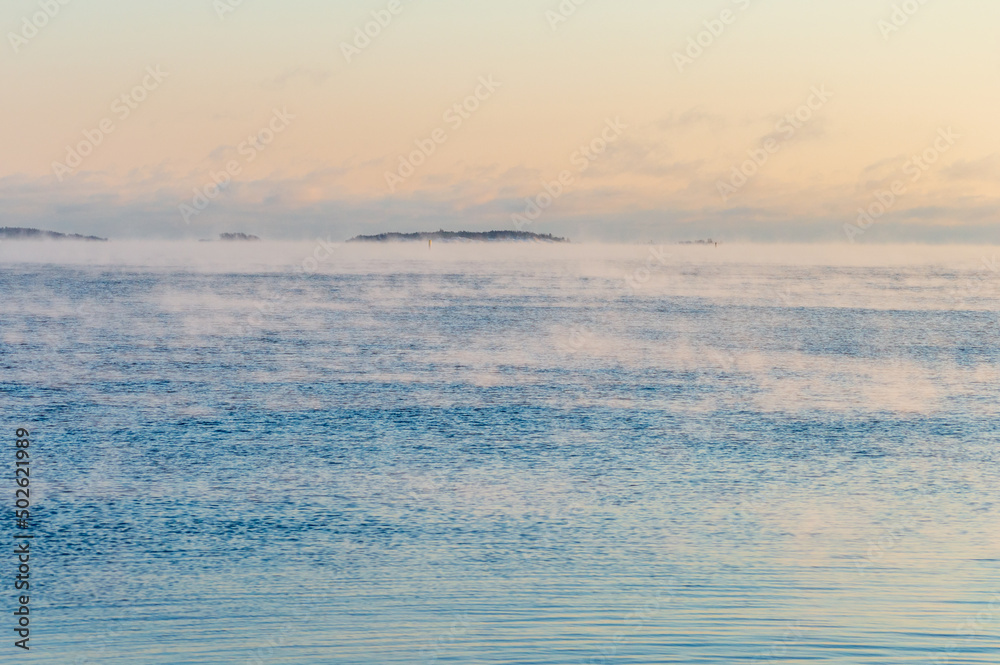 Fototapeta premium Minimal view of the sea from Helsinki coastline. The weather is so cold that the water freezes and crates a light mist on its surface