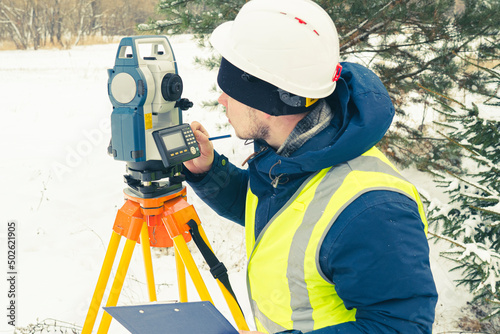 cadastral works with an electronic total station, a male cadastral engineer performs measurements with a tool for geodetic measurements on the ground selective focusing, tinting. photo