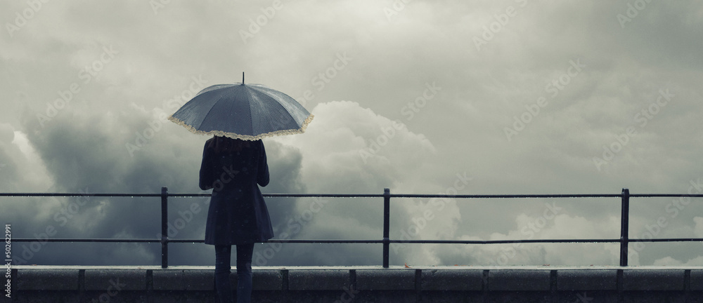 Woman with umbrella standing on the rain during autumn storm  - obrazy, fototapety, plakaty 