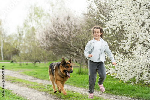 little girl running with a dog in a flower garden © Angelov