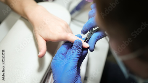 Woman in nail salon doing manicure by beautician with nail clippers