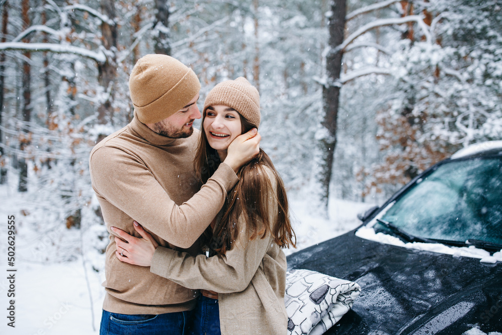 Obraz premium winter love story. couple in love in the winter forest hugging. woman and man in beige clothes
