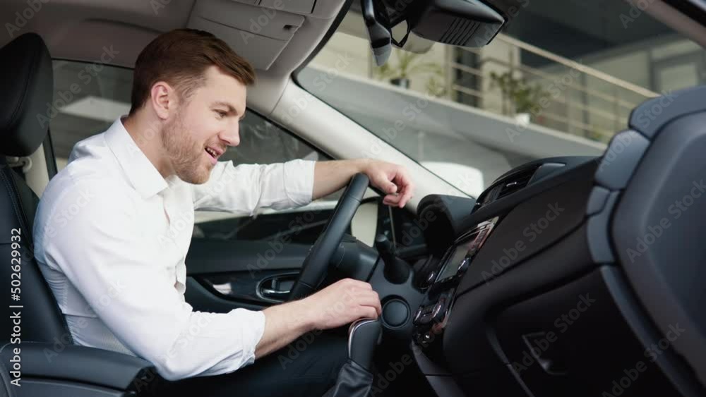 The man is pleasantly surprised by the functions of the new car. Businessman examine vehicle before making purchase. Buy car The man is pleasantly surprised by the functions of the new car. Businessman examine vehicle before making purchase. Buy car