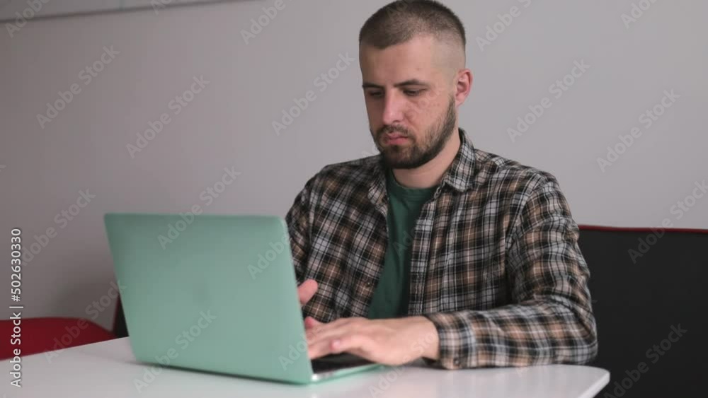 The guy in the shirt is working on the computer, working remotely. Freelancer. The guy in the shirt is working on the computer, working remotely. Freelancer.