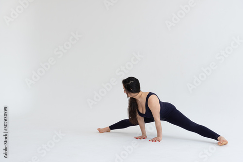 Young beautiful woman practicing yoga on a white background. Young beautiful girl doing exercises at home. Harmony, balance, meditation, relaxation, healthy lifestyle concept 