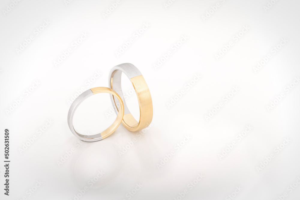 Pair of elegant white and yellow gold wedding rings in a studio shot Pair of elegant white and yellow gold wedding rings in a studio shot