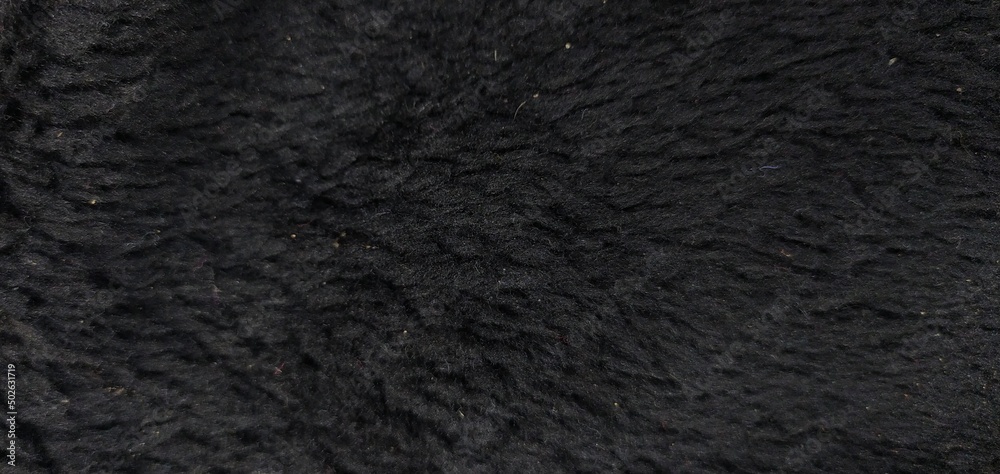 Smooth soft dirty black color furry, fluffy and hairy artificial sheep skin plush fur wool rug texture cloth knitted coarse background surface pattern for beauty and fashion concepts. Close up view. Smooth soft dirty black color furry, fluffy and hairy artificial sheep skin plush fur wool rug texture cloth knitted coarse background surface pattern for beauty and fashion concepts. Close up view.