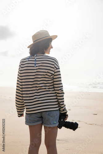 Obraz na płótnie Photo of a young and attractive woman with a photo camera wearing summer clothes at the beach. Photography, holidays, travel. w salonie