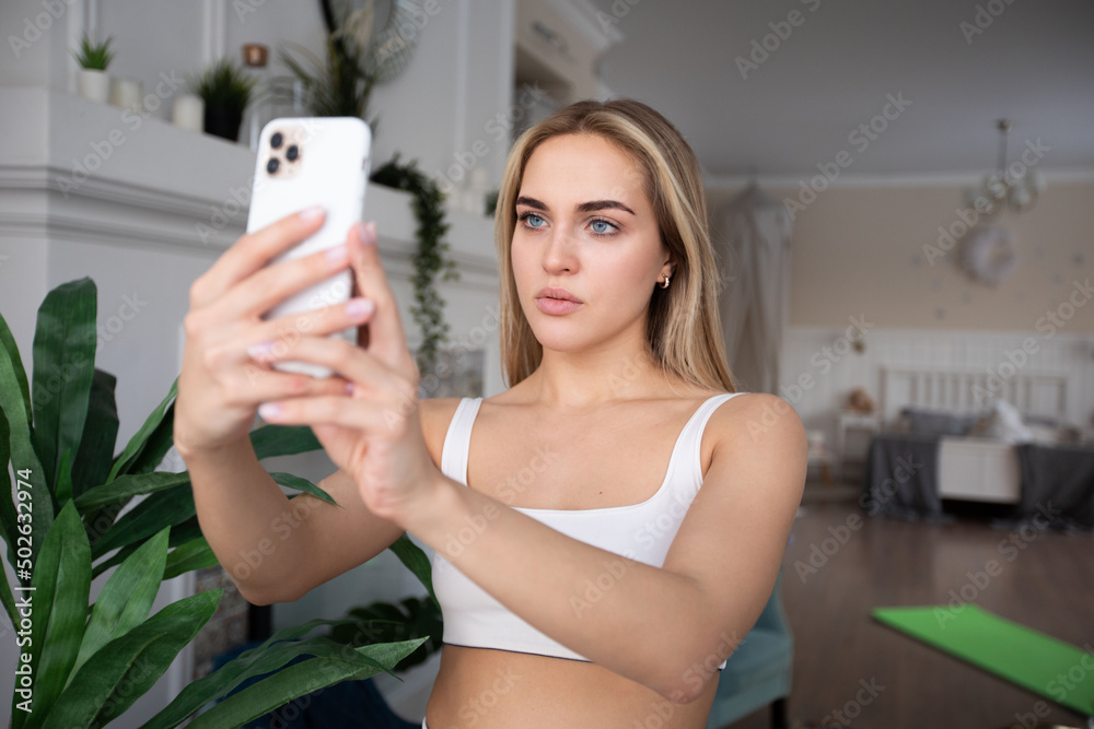 Attractive blonde woman in sportswear taking selfie at home. Attractive blonde woman in sportswear taking selfie at home.