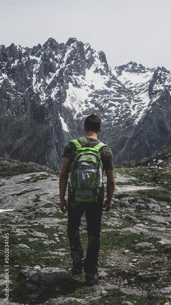 One person from behind hiking with the snowy mountains in the background