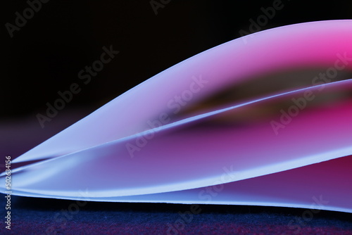 Hojas de cartulina para artesanìas con luz horizontal azul y rosa suave, forma un bello diseño abstracto en el espacio de lìneas en curvas con fondo negro