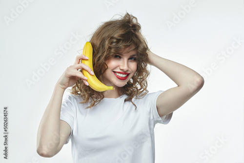 attractive girl holds a banana in her hands and pretends to call through it