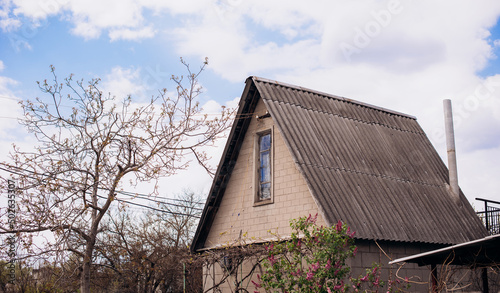 part of a big rural house with a gray slate roof against a sky © VlaDee