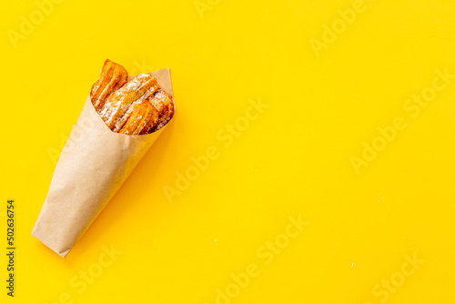 Street food dessert churros in paper bag with sugar photo