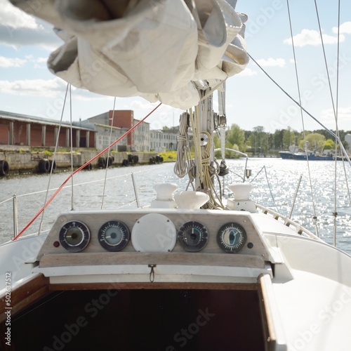 Sloop rigged sailboat moored to a pier in a yacht marina. View from a cockpit. Transportation, sailing, yachting, sport, recreation, leisure activity, cruise, tourism, lifestyle, service, repair theme