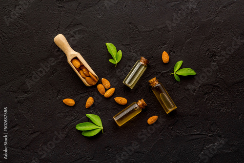 Sweet almond oil in glass jar and almond seeds with green leaf