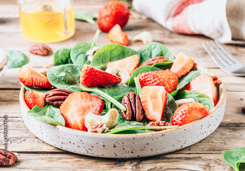 Fresh strawberry salad with spinach leaves and nuts.