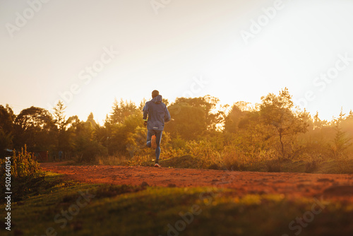 Kenyan marathoner during training in Africa. City of Iten, Kenya. Marathon training on red dirt roads in Africa. Near the town of Eldored. Great Rift Valley Region. Sunrise light, White background photo