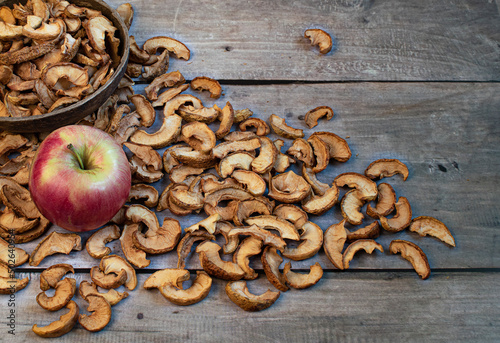 Ripe apple and dried apples in a bowl on wooden background . Harvesting and drying apples. Dried apple slices on the table. Dried fruit chips. Healthy vegan food