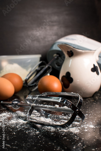 Milk, flour, eggs and blender stuff on a black table in the kitchen 