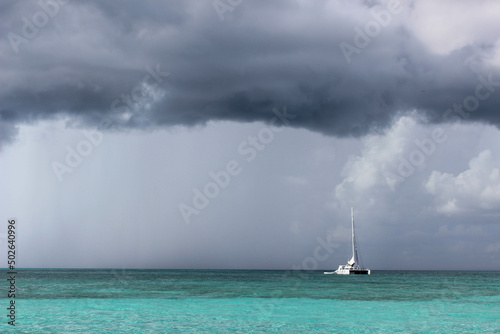 Вoat on the horizon of the sea. Turquoise water and dark sky before a thunderstorm. Storm is coming in Caribbean Sea.