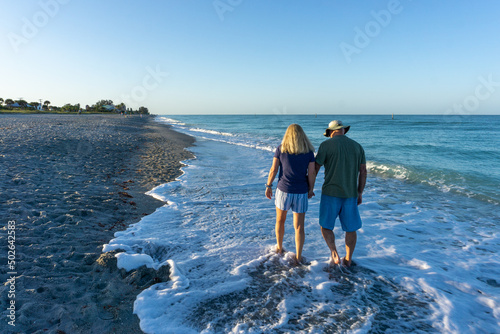 Old couple hold hands on beach in Florida