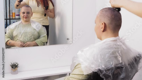 A woman in a barbershop shaved baldly shaves her head clean. Medium plan photo