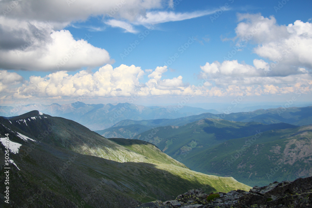 Beautiful clouds over high mountain ranges at the Karatyurek pass in Altai, distant view, summer