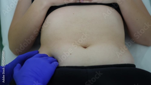 Top view belly of slim young Caucasian woman lying on examination couch with doctor hand pressing abdomen. Unrecognizable man checking ill patient in hospital indoors. Gastrointestinal tract diseases