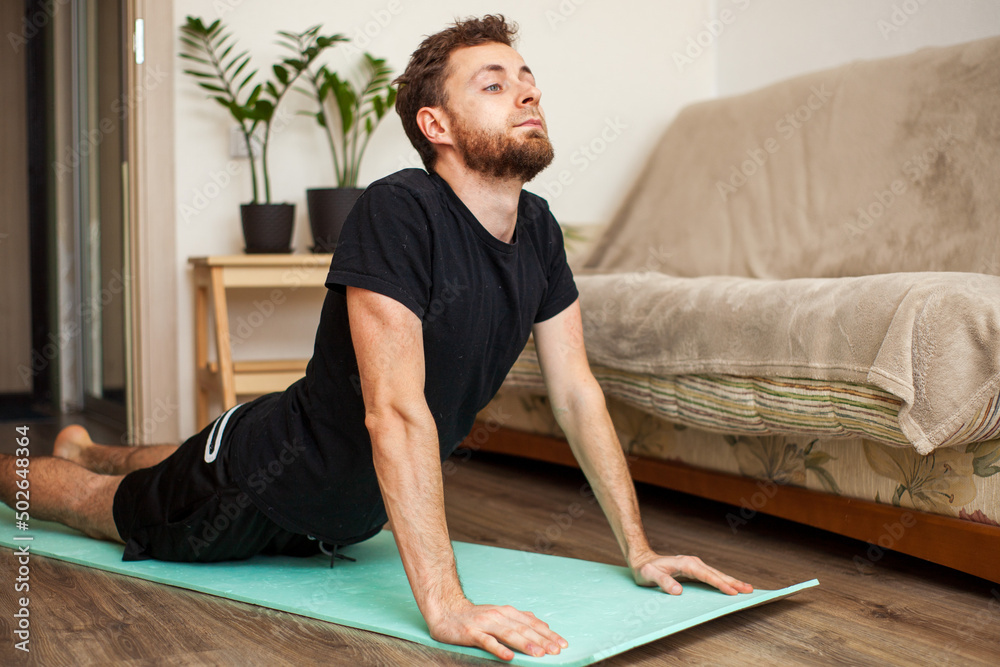 Fototapeta premium young man doing yoga fitness workout at home on yoga mat