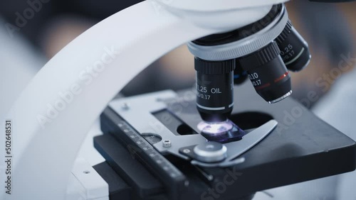 researcher examines samples of a modern electron diode microscope close-up in a modern biochemical laboratory.