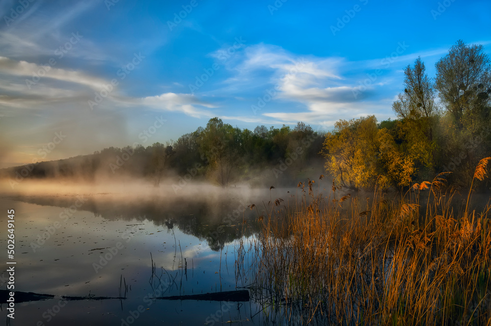 The river in the early morning in the fog in early spring. Calm scenic morning landscape on the river.