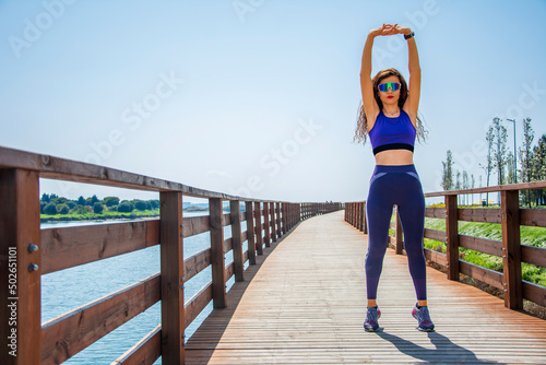 Fototapeta Naklejka Na Ścianę i Meble -  Woman stretching her body on bridge at lake