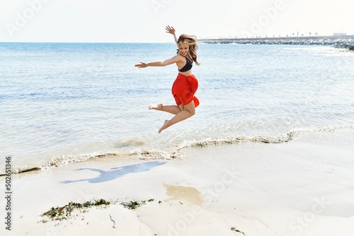 Young cuacasian girl smiling happy dancing at the beach.