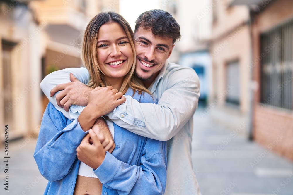 Fototapeta premium Young man and woman couple hugging each other standing at street