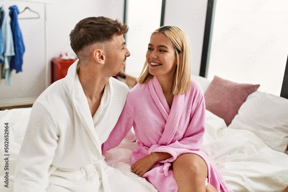 Young caucasian couple smiling happy and hugging sitting on the bed at home.
