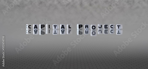 capital project word or concept represented by black and white letter cubes on a grey horizon background stretching to infinity