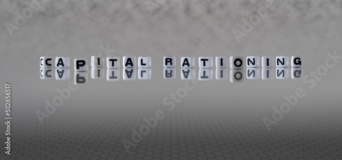 capital rationing word or concept represented by black and white letter cubes on a grey horizon background stretching to infinity