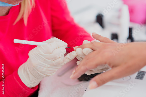 Manicure process. The master polishes the nail french manicure to client in beauty salon