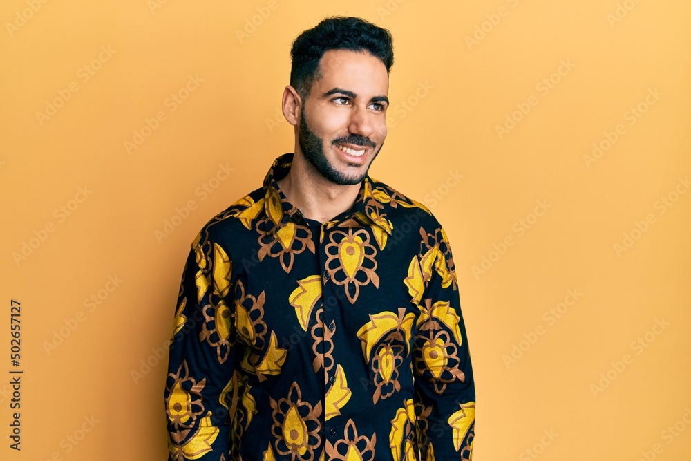 Young hispanic man wearing casual shirt looking away to side with smile on face, natural expression. laughing confident. Young hispanic man wearing casual shirt looking away to side with smile on face, natural expression. laughing confident.