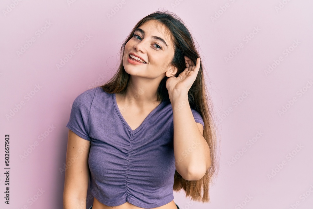 Young caucasian woman wearing casual clothes smiling with hand over ear listening an hearing to rumor or gossip. deafness concept. Young caucasian woman wearing casual clothes smiling with hand over ear listening an hearing to rumor or gossip. deafness concept.