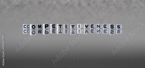 competitiveness word or concept represented by black and white letter cubes on a grey horizon background stretching to infinity