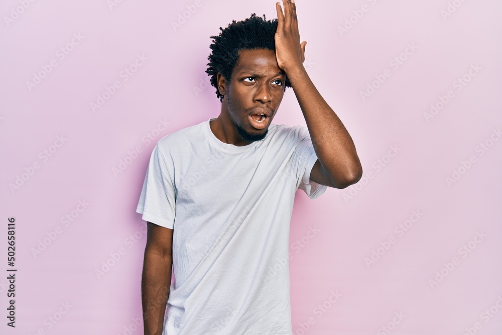 Young african american man wearing casual white t shirt surprised with hand on head for mistake, remember error. forgot, bad memory concept. Young african american man wearing casual white t shirt surprised with hand on head for mistake, remember error. forgot, bad memory concept.