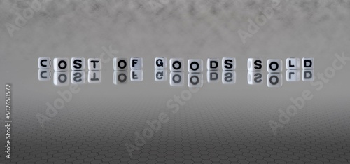 cost of goods sold word or concept represented by black and white letter cubes on a grey horizon background stretching to infinity