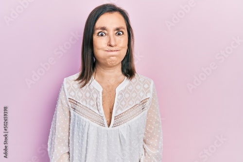 Middle age hispanic woman wearing casual clothes puffing cheeks with funny face. mouth inflated with air, crazy expression. © Krakenimages.com