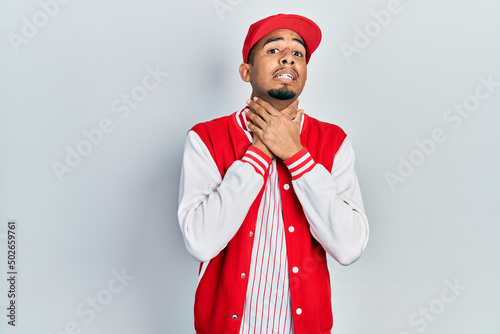 Young african american man wearing baseball uniform shouting and suffocate because painful strangle. health problem. asphyxiate and suicide concept.
