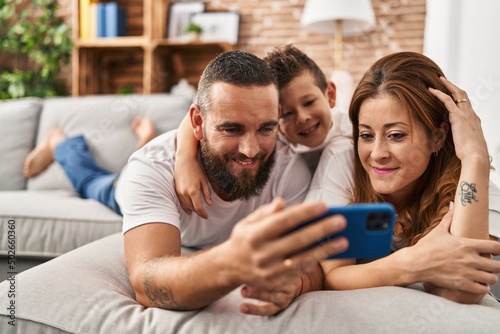Family make selfie by smartphone lying on sofa at home