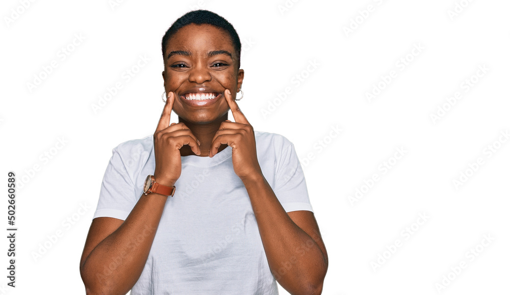 Young african american woman wearing casual white t shirt smiling with open mouth, fingers pointing and forcing cheerful smile Young african american woman wearing casual white t shirt smiling with open mouth, fingers pointing and forcing cheerful smile