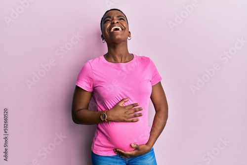 Young african american woman expecting a baby, touching pregnant belly crazy and mad shouting and yelling with aggressive expression and arms raised. frustration concept.