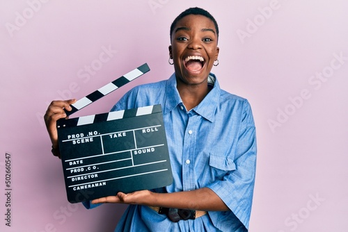 Photo Young african american woman holding video film clapboard celebrating crazy and amazed for success with open eyes screaming excited